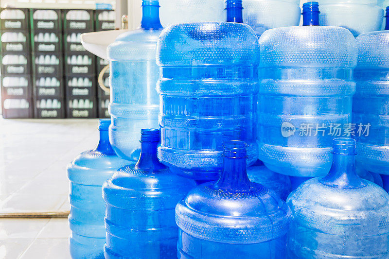 蓝色塑料瓶或蓝色加仑的饮用水堆放在饮用水工厂循环使用饮用水。水厂经营理念