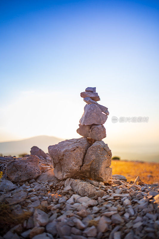 石头堆叠与平衡的石头在模糊的山背景在日落温暖的光股票照片