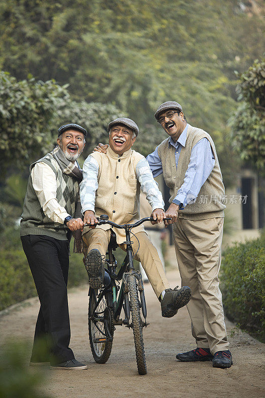 欣喜若狂的老人和朋友在公园学习骑自行车