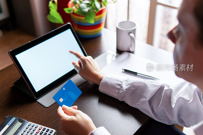 一名女子使用电子平板电脑和信用卡，在网上订购购物。在家工作的概念