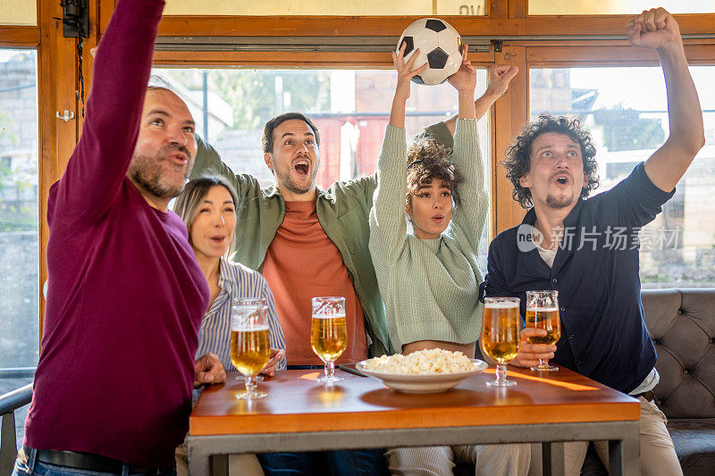 人们在酒吧里观看足球比赛欢呼