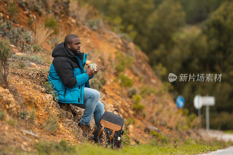 在山里远足的男人喝着热咖啡