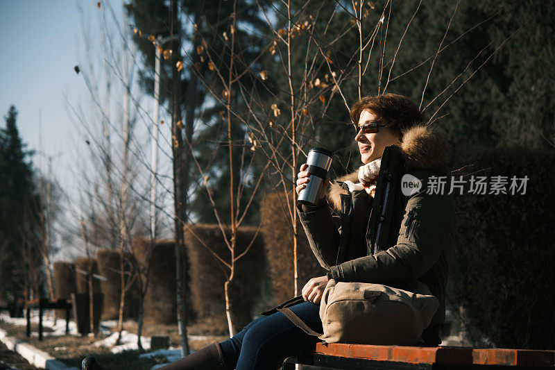 冬天的自然公园里，一名女子正在喝热茶
