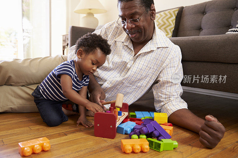 爷爷和孙子在家里的地板上玩玩具