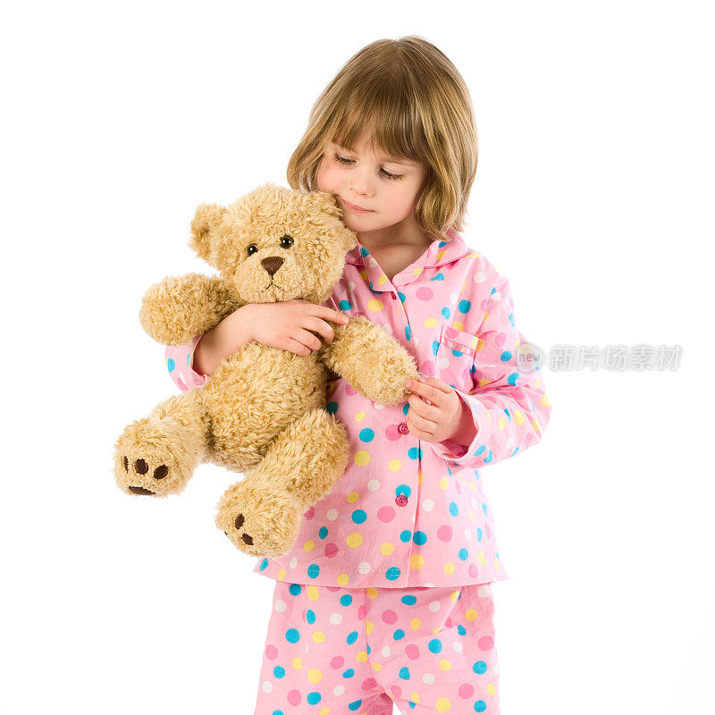 孩子抱着穿着粉红色睡衣的泰迪熊