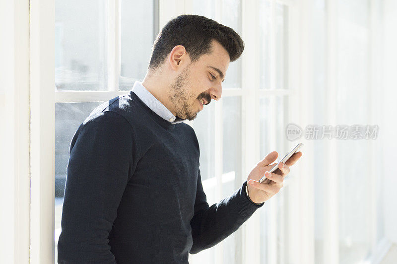 英俊的商人在看智能手机上的短信