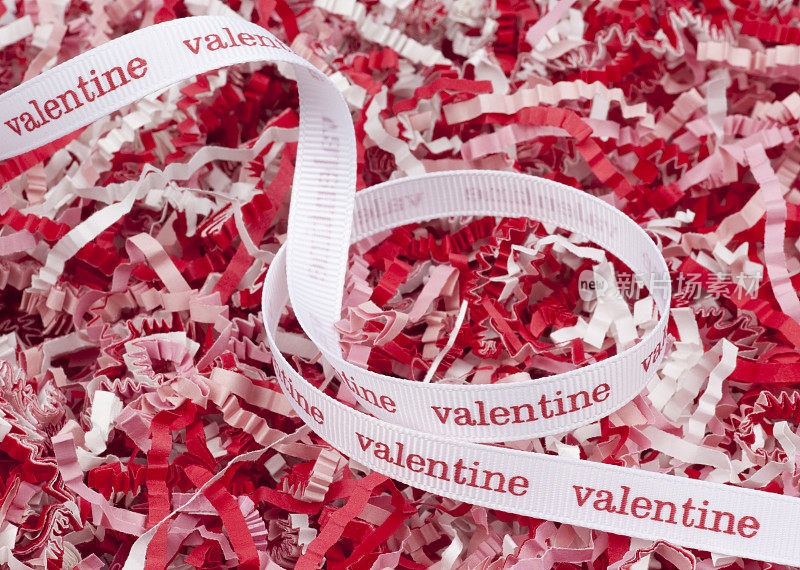 节日的情人节丝带在红色和粉红色的纸屑，背景