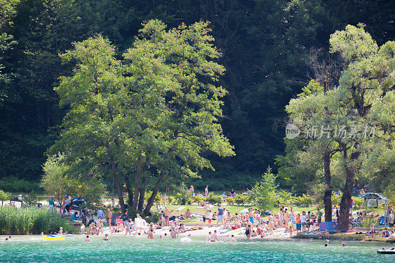 夏天，树木为拥挤的湖滨海滩提供了阴凉