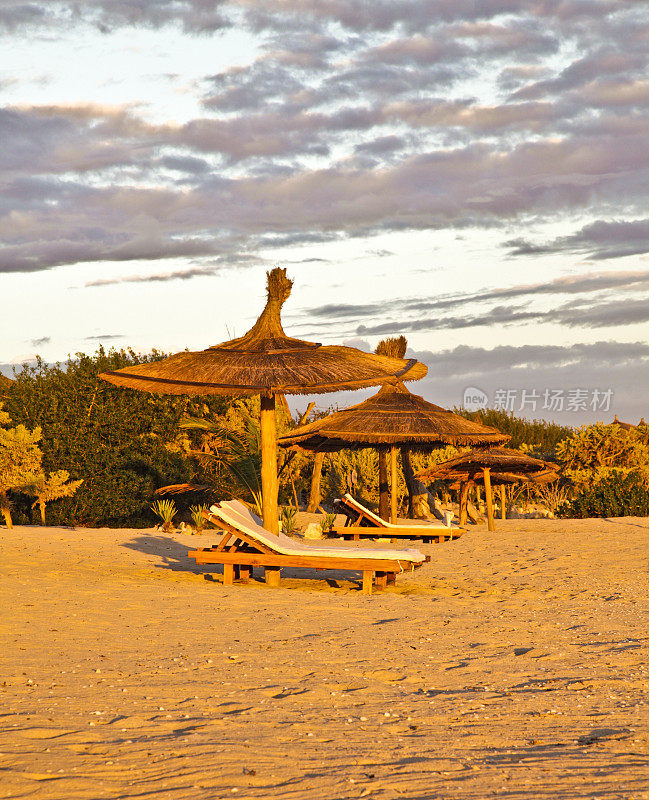 茅草遮阳伞(Palapas)在一个荒芜的马达加斯加海滩日落