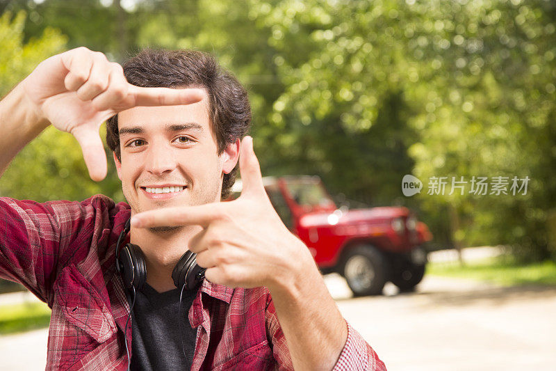 小伙子们:年轻的成年男性用手指制造框架。吉普车的背景。