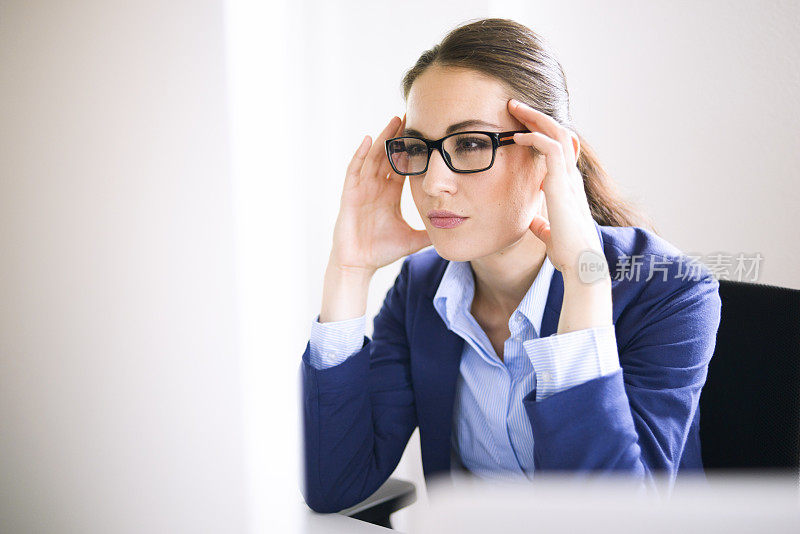 戴眼镜专注于电脑显示器的女商人
