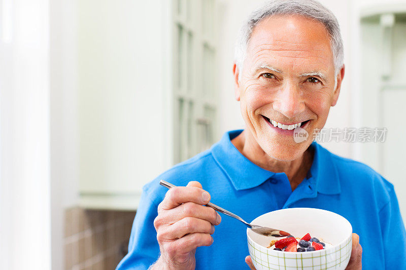 老年男子享受冷冻酸奶与新鲜浆果。