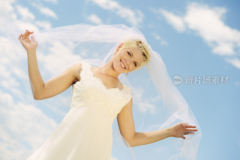 美丽的新娘站在多云的蓝天