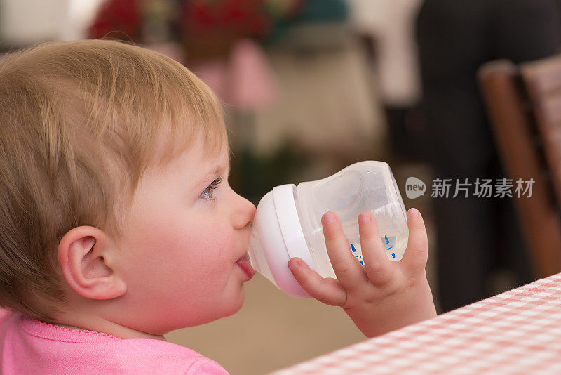 漂亮的小女孩喝着奶瓶里的牛奶