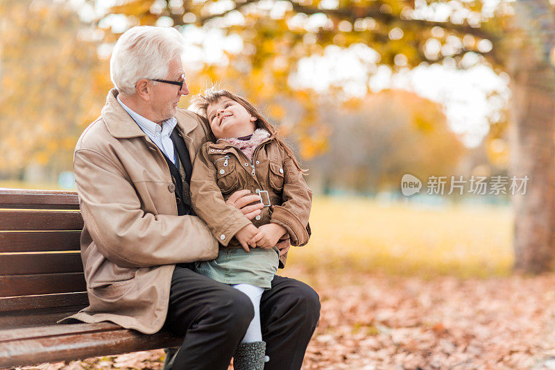 微笑的爷爷和孙女在大自然中交谈。