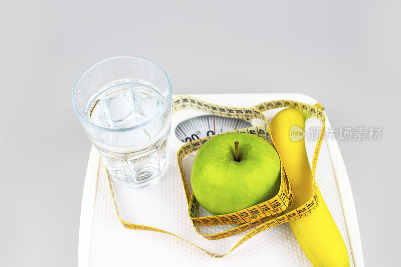 饮食的概念。苹果香蕉杯水卷尺