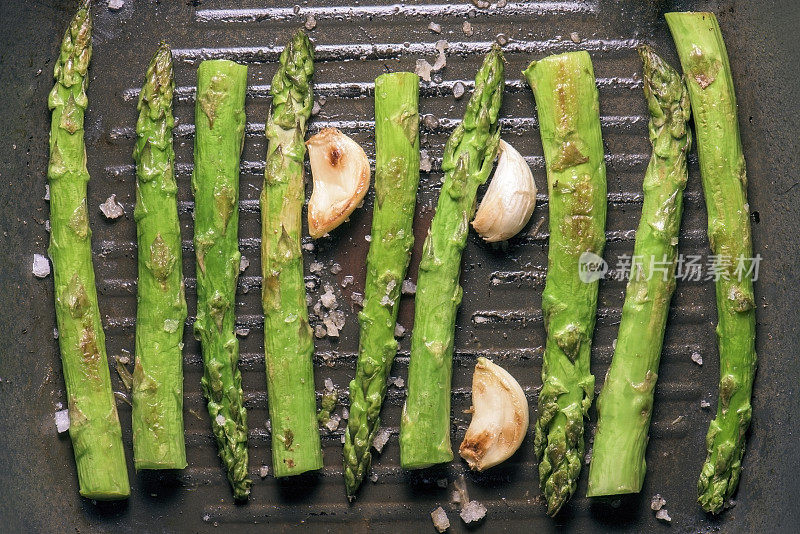 新鲜的绿芦笋与大蒜在金属煎锅中烹饪