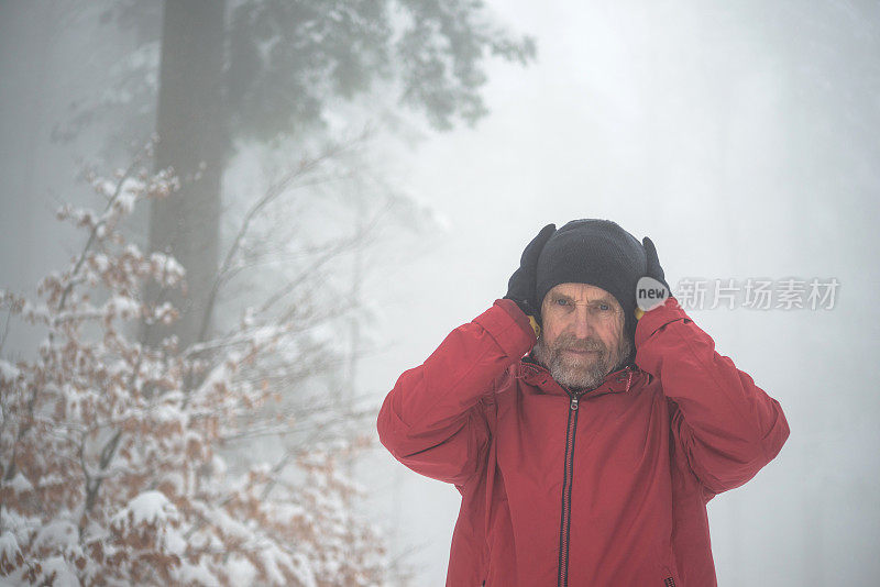 冒险的高级男子徒步旅行在雾森林，下雪，阿尔卑斯山，欧洲