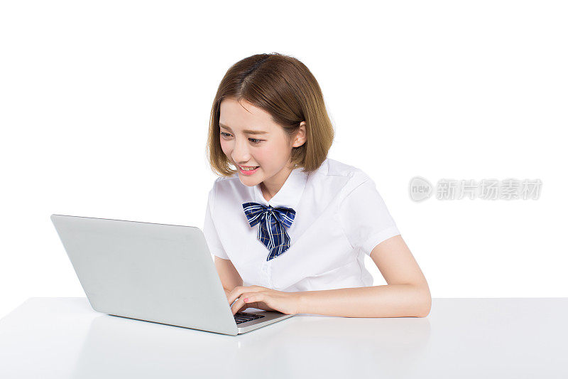 美丽的少女使用笔记本电脑在桌子上的白色工作室