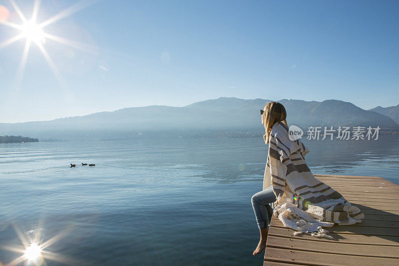 年轻女子在湖边码头上休息，看风景