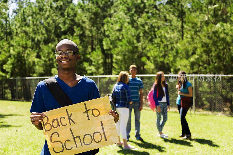 一名非洲裔少年举着“返校”的牌子。朋友。