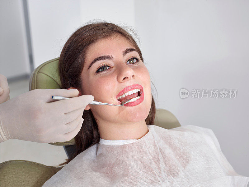 牙医正在检查年轻女子的牙齿