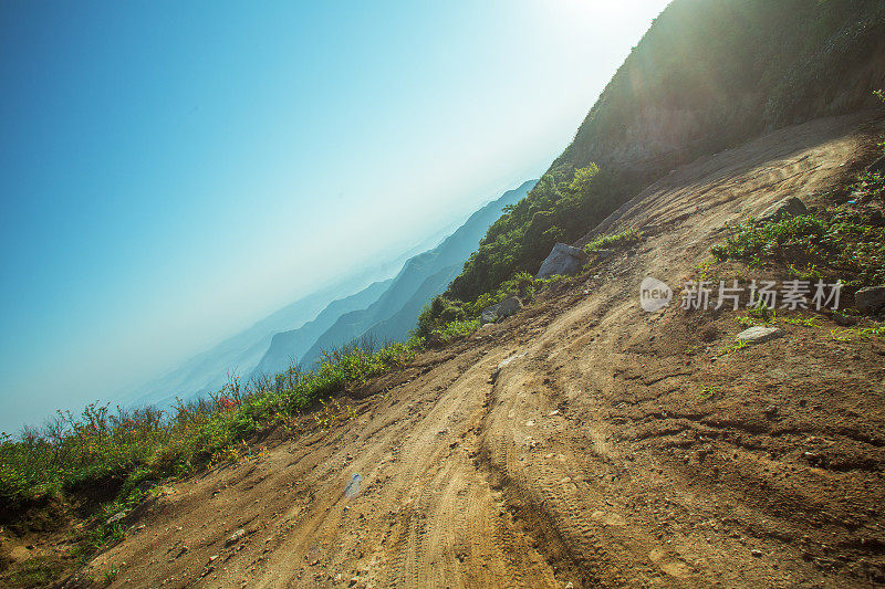 在夕阳下转弯泥泞的道路，轮胎印为汽车商业