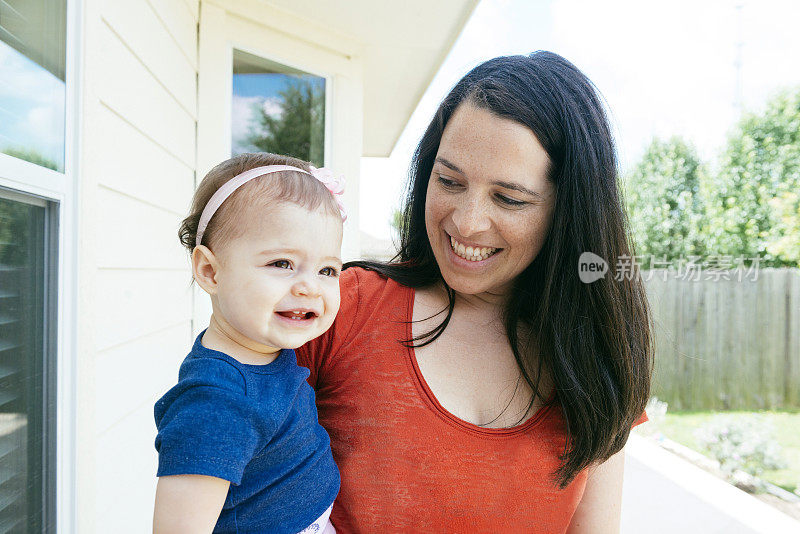 微笑的千禧母亲抱着婴儿女孩在美国以外的家