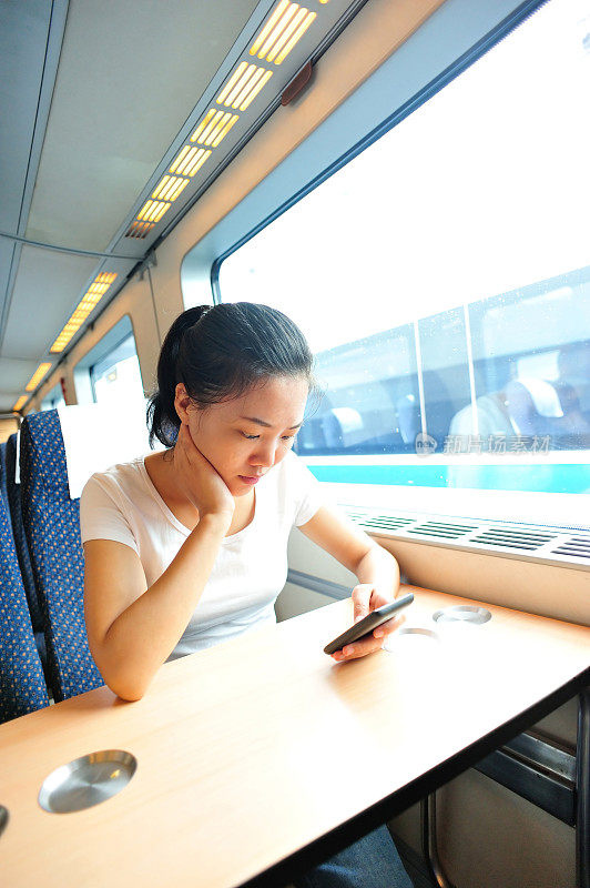 年轻女子在高铁上使用智能手机