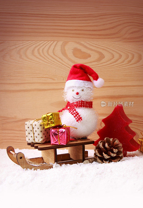 雪人和圣诞礼物在雪橇上孤立的木头背景