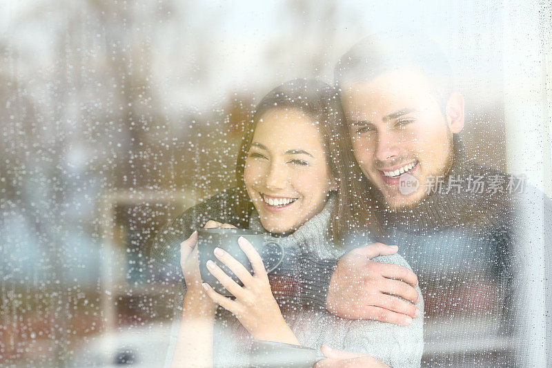 一对乐观的夫妇在雨天透过窗户看