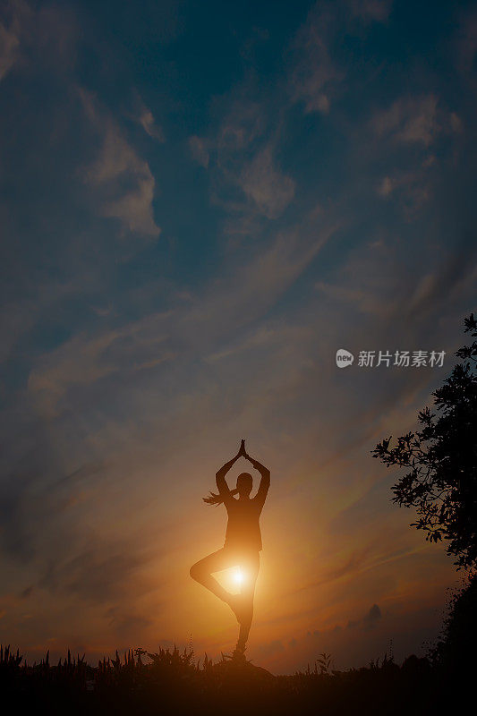 夕阳下一个瑜伽女人的剪影