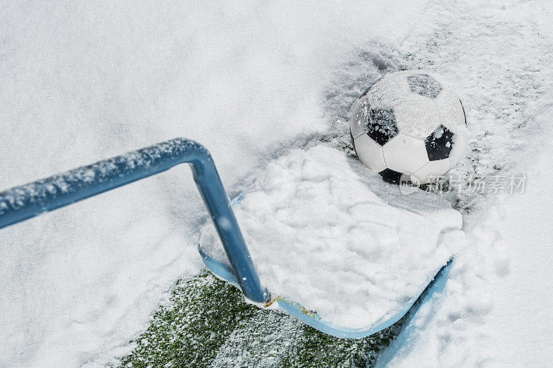 雪铲清理雪旁边的足球被雪覆盖，坐在院子里的一条线