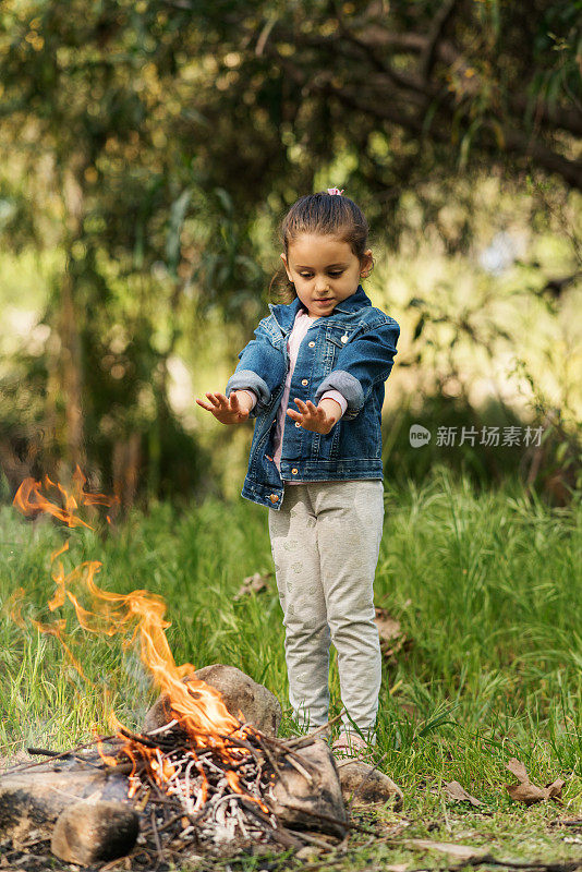 幼童在篝火旁暖手