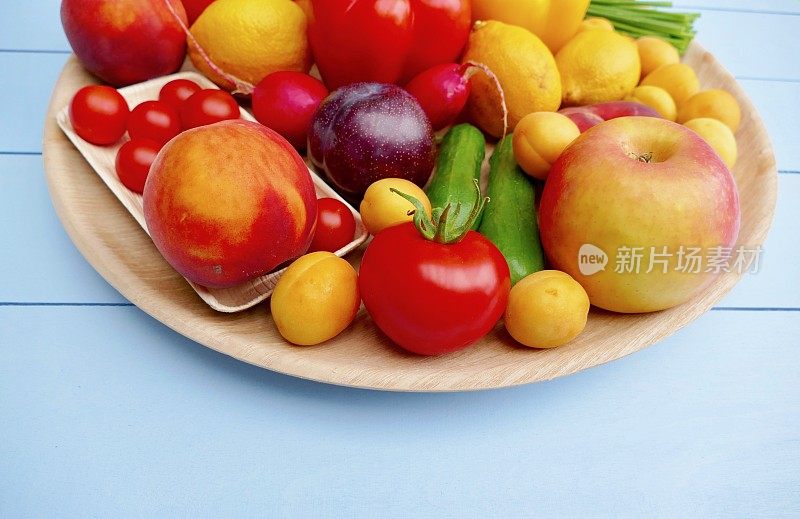 石灰绿色的桌子上放着一个装有水果和蔬菜的圆形木盘子