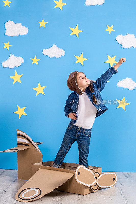 一个穿着飞行员服装的小女孩正在玩，梦想着飞越云层