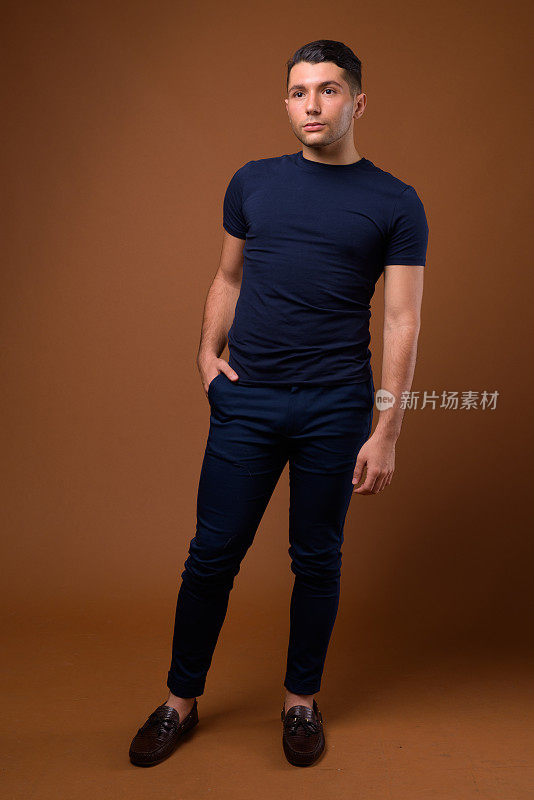 工作室拍摄的年轻英俊的男子穿着蓝色衬衫，以彩色背景