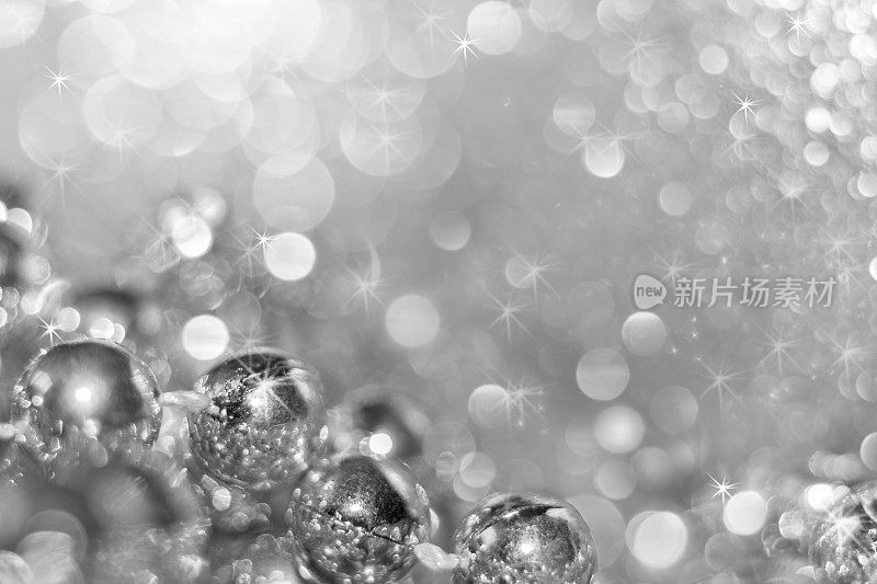 抽象的银色圣诞黑白背景与软焦点。左下角的圆珠和漂亮的散景，上面有星号。