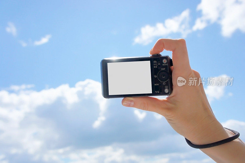 手持数码相机。女孩的手拿着相机对着天空。为你的图片或文本留出空间。