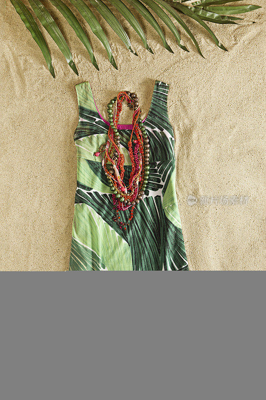 时尚连衣裙与项链上的沙子背景
