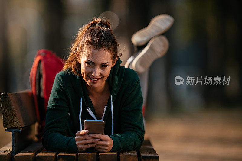 漂亮的年轻运动女性与智能手机在户外