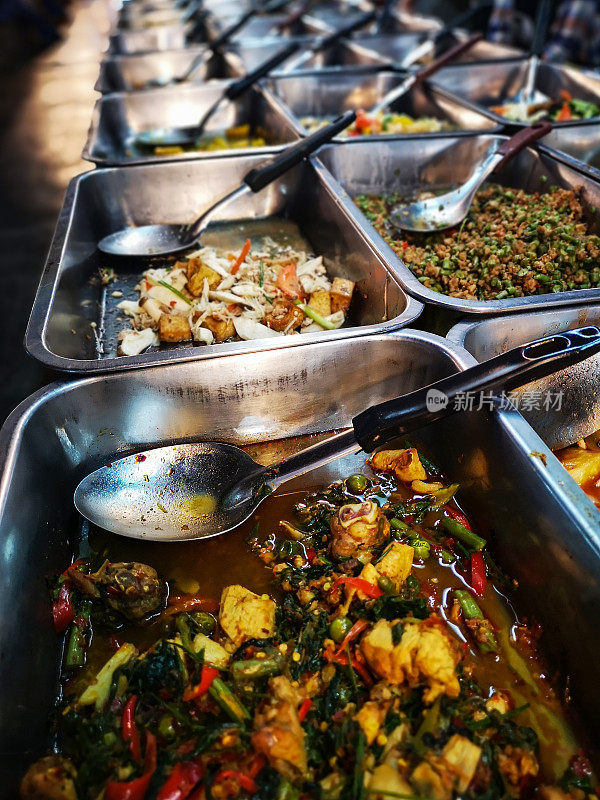 传统快餐泰式食品托盘与泰国菜咖喱饭和汤在泰国食品市场展出。顾客选择他们喜欢的菜，然后他们会被提供给他们的选择，这是在白色的泰国蒸饭上面。