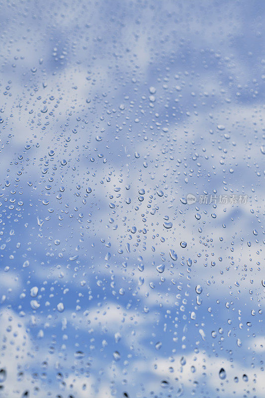 暴风雨过后，透过窗户可以看到蓝天和白云的雨滴。