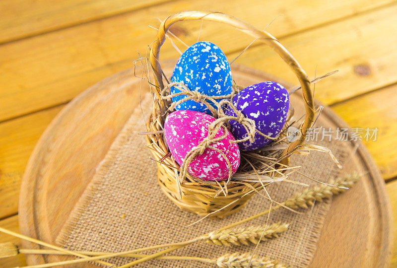 近距离拍摄的一组三个彩色的手画复活节彩蛋编织篮子在木桌上