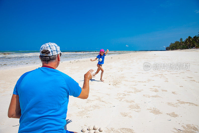父亲和女儿在白色沙滩上玩耍