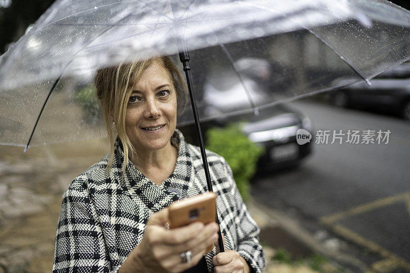 一个女人在户外用手机撑伞的肖像