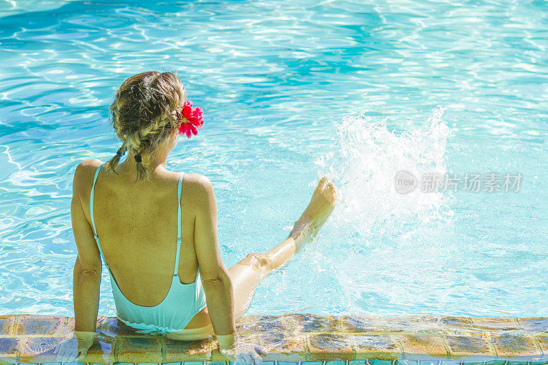 年轻女子在泳池边享受鸡尾酒