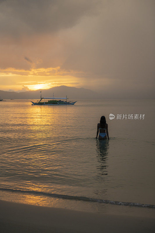 在菲律宾巴拉望的巴顿港，一名女子在夕阳下步入平静的大海