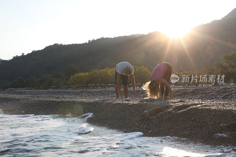 朋友们在日出的时候在海滩上做瑜伽