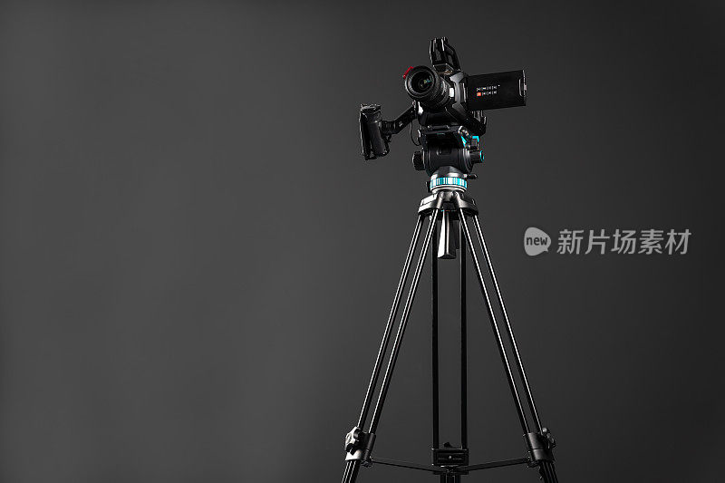 专业的视频影院相机上的相机三脚架上的黑色工作室背景复制空间，低角度视角